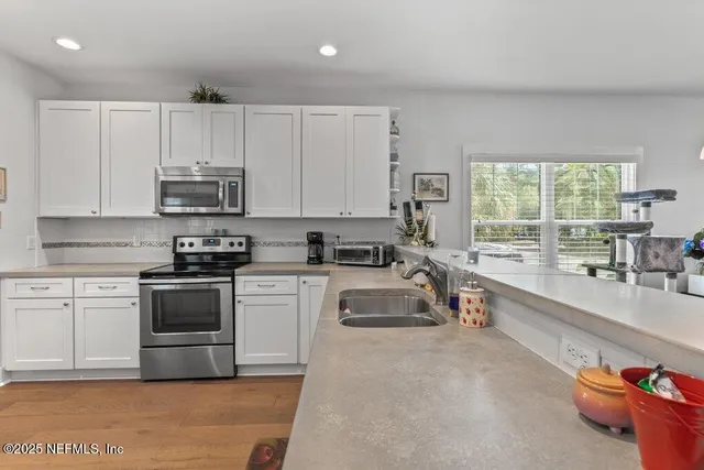 a kitchen with stainless steel appliances granite countertop white cabinets and a stove top oven