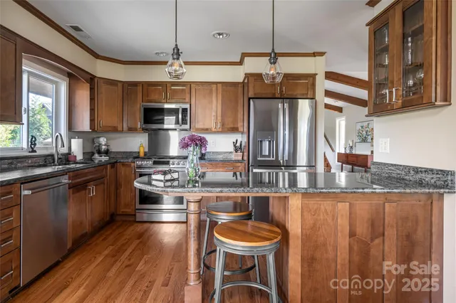 a kitchen with stainless steel appliances granite countertop a stove top oven a refrigerator and cabinets