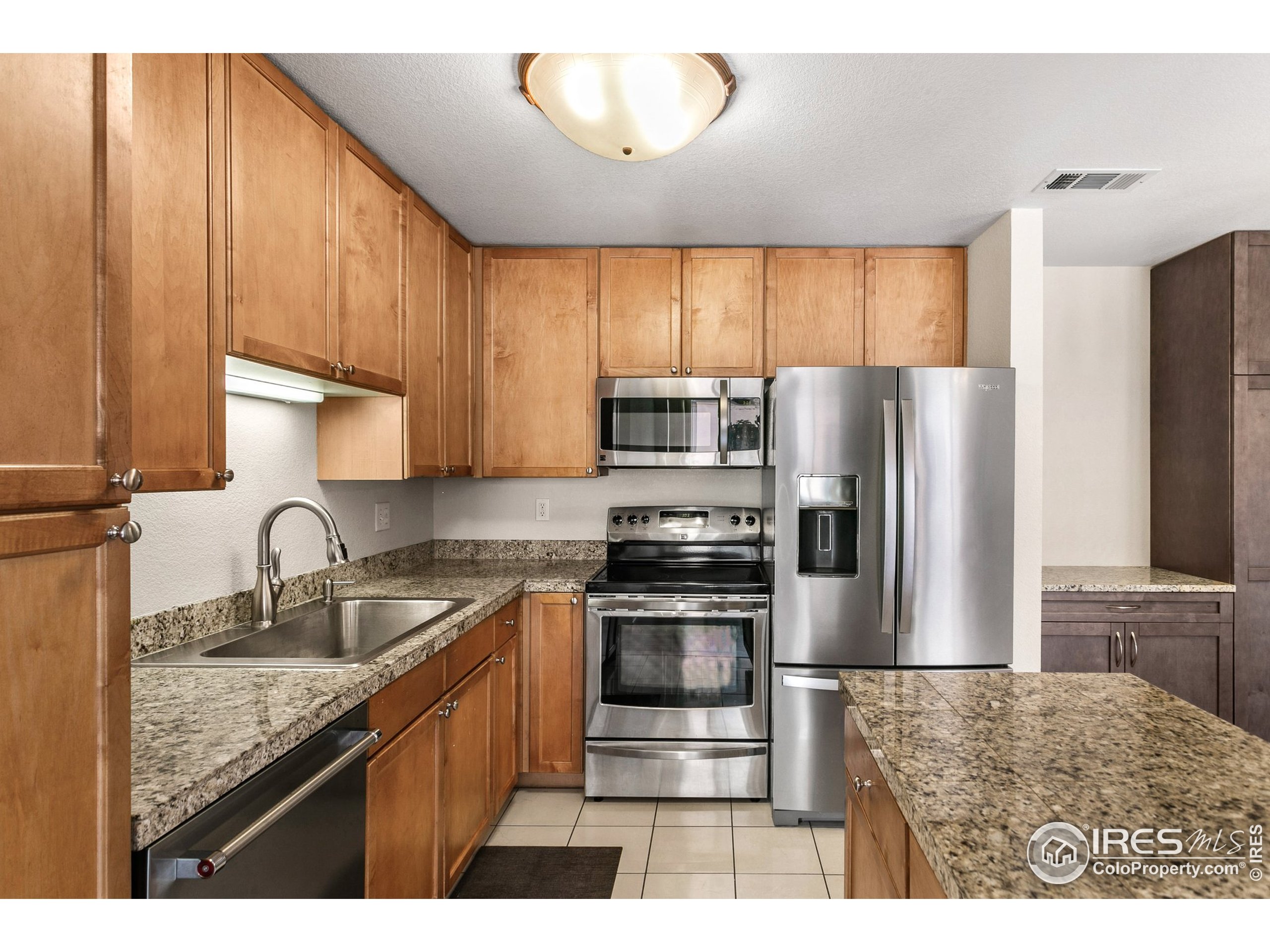 4500 Baseline Road, Unit 3302 Boulder, CO 80303 - Photo 4 of 22 a kitchen with kitchen island granite countertop a sink refrigerator and cabinets