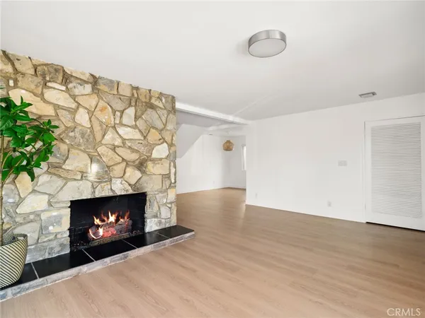 a view of an empty room with wooden floor and fireplace