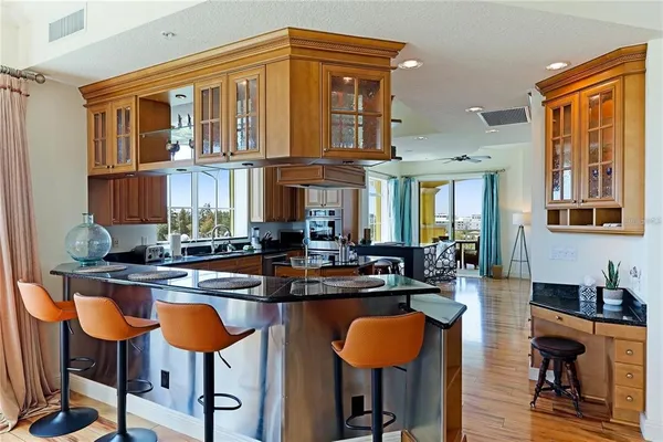 a kitchen with stainless steel appliances granite countertop a table chairs in it and wooden floors