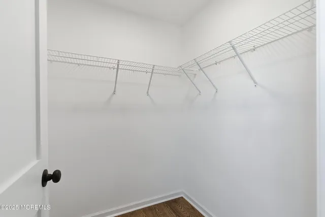 an empty room with wooden floor chandelier fan and windows