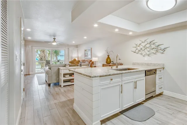 a kitchen with kitchen island granite countertop a sink cabinets and wooden floor