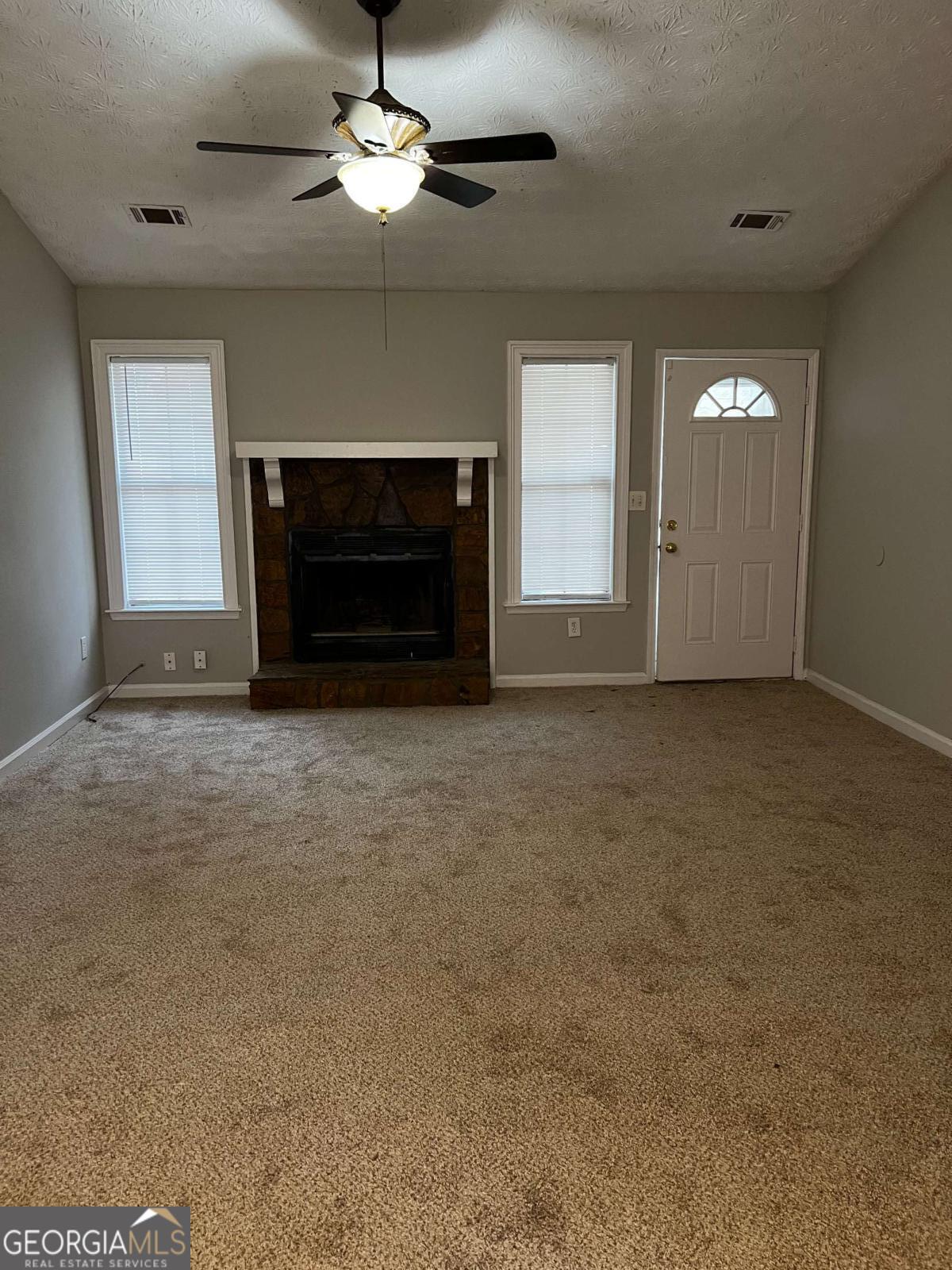 164 Adrian Drive Stockbridge, GA 30281 - Photo 2 of 12 an empty room with windows fireplace and fan