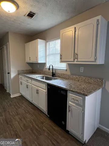 a kitchen with granite countertop cabinets sink and window
