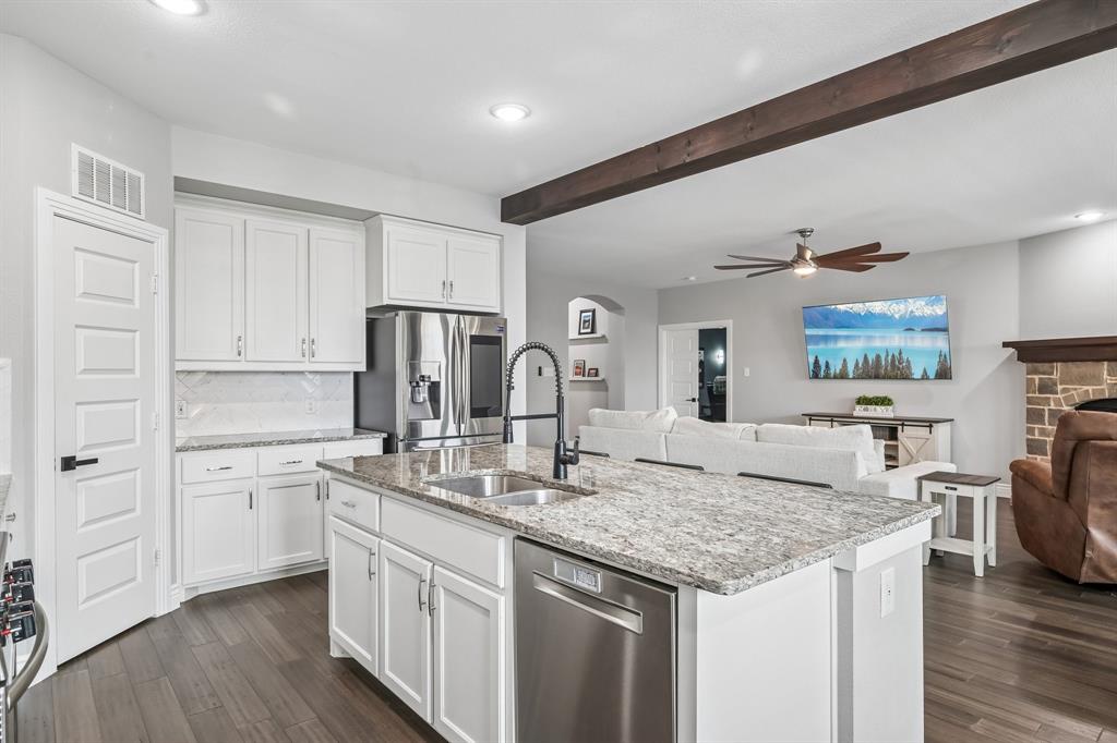 1805 Huntsman Way Forney, TX 75126 - Photo 10 of 34 Open-concept kitchen featuring white cabinetry, light-toned granite countertops, a stainless steel refrigerator, and wood-finish flooring