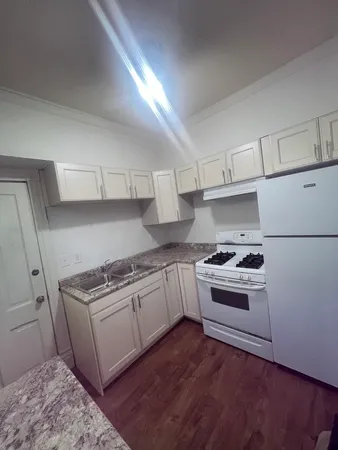 a kitchen with granite countertop wooden floors and white stainless steel appliances