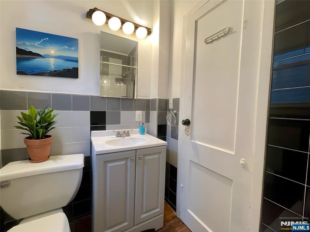 145 Maple Street, Unit 2 Kearny, NJ 07032 - Photo 2 of 3 a bathroom with a toilet a sink and a mirror