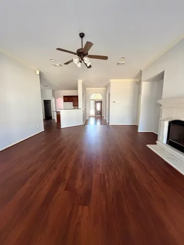 a view of a livingroom with wooden floor a ceiling fan and staircase