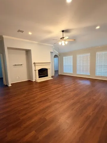 an empty room with wooden floor ceiling fan and windows