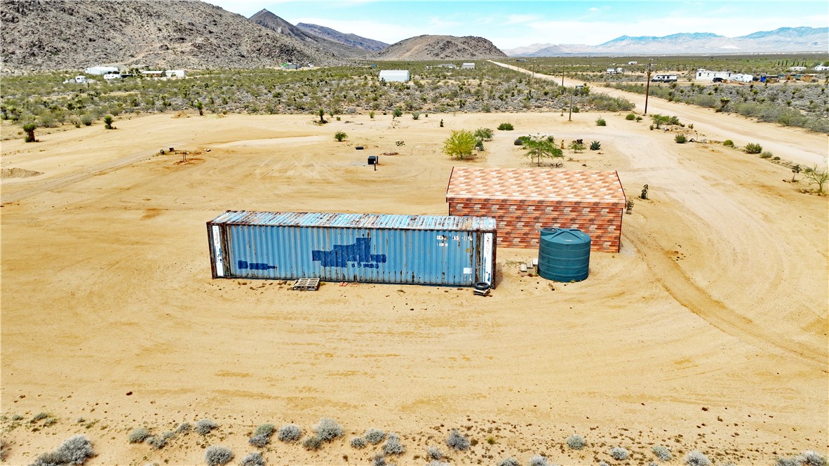 5649 Davis Road Golden Valley, AZ 86413 - Photo 5 of 24 Expansive desert property featuring a detached brick-pattern structure, a large blue storage container, and a green water tank
