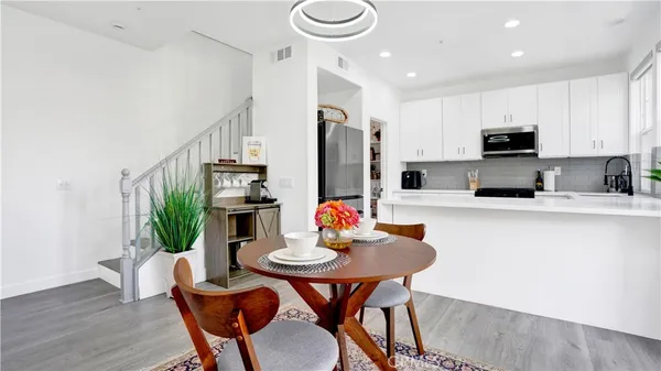 a kitchen with stainless steel appliances kitchen island granite countertop a dining table chairs and a refrigerator
