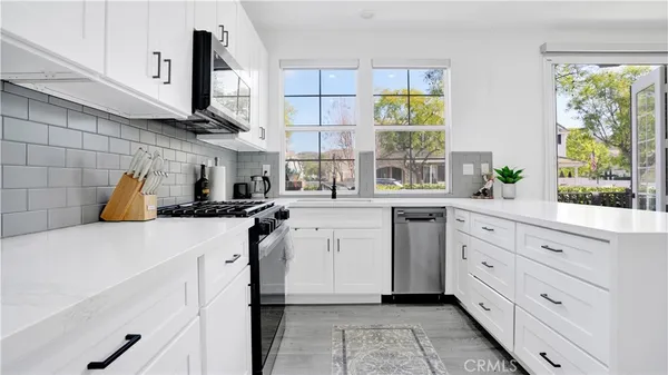 a kitchen with white cabinets and window