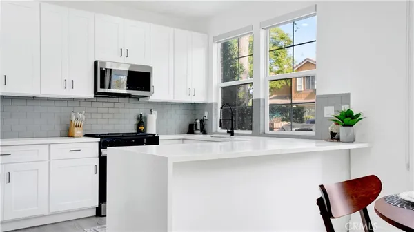 a kitchen with stainless steel appliances granite countertop a stove a sink dishwasher and white cabinets with wooden floor