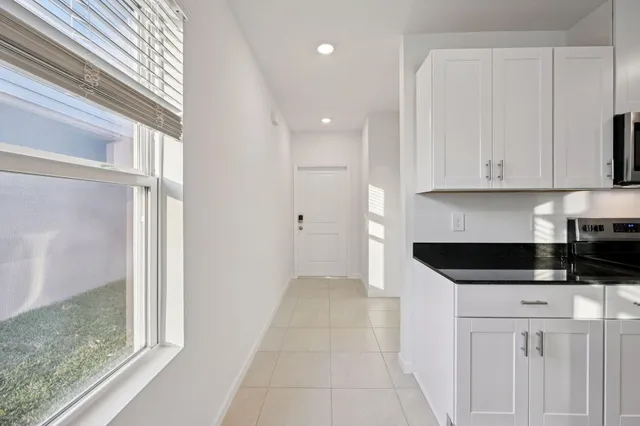 a kitchen with granite countertop white cabinets and black appliances
