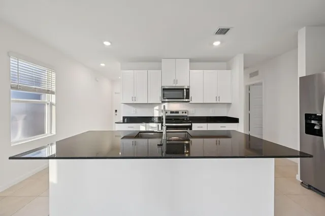a kitchen with kitchen island a counter top space a sink stainless steel appliances and cabinets