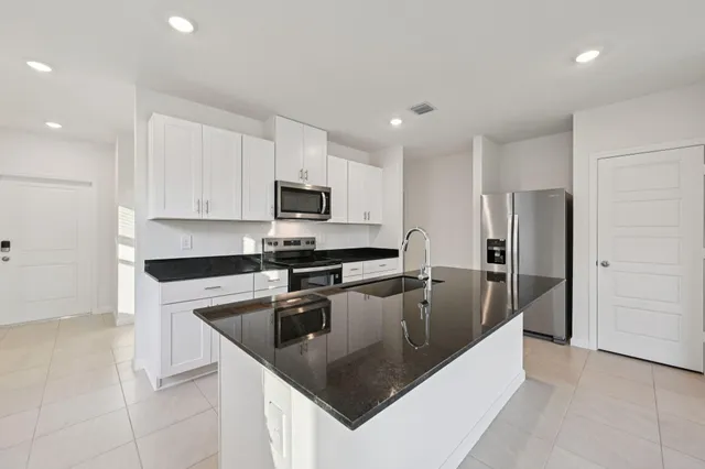 a kitchen with granite countertop a sink a counter top space stainless steel appliances and cabinets