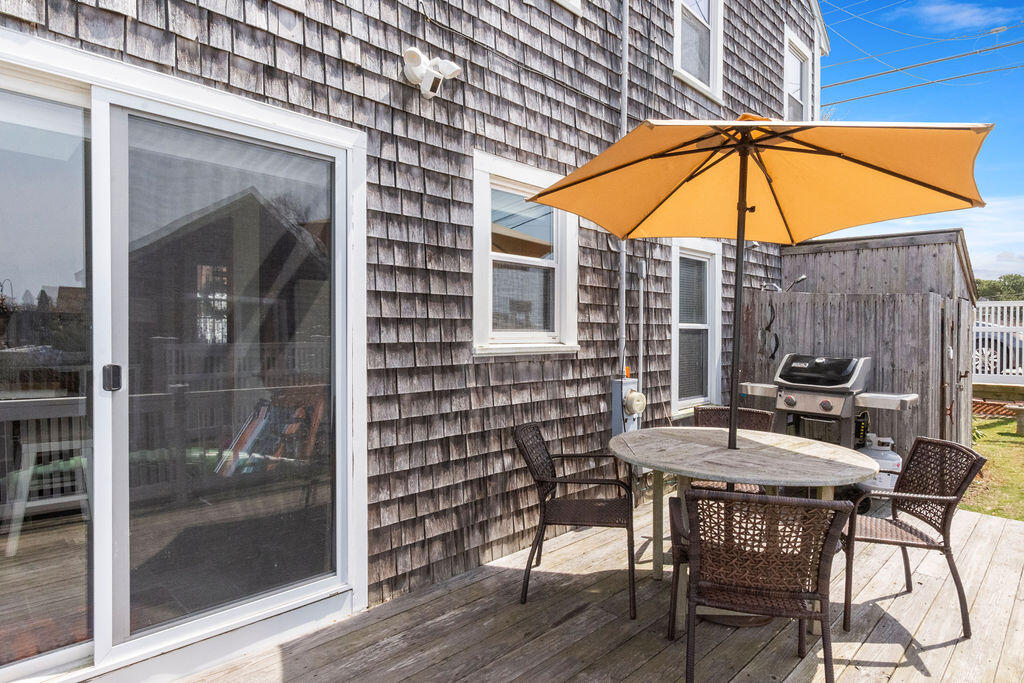 14 Lower County Road Dennis Port, MA 02639 - Photo 46 of 56 a patio with a table and chairs under an umbrella