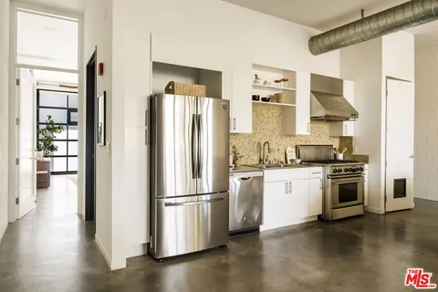 a kitchen with stainless steel appliances granite countertop a refrigerator and a stove top oven