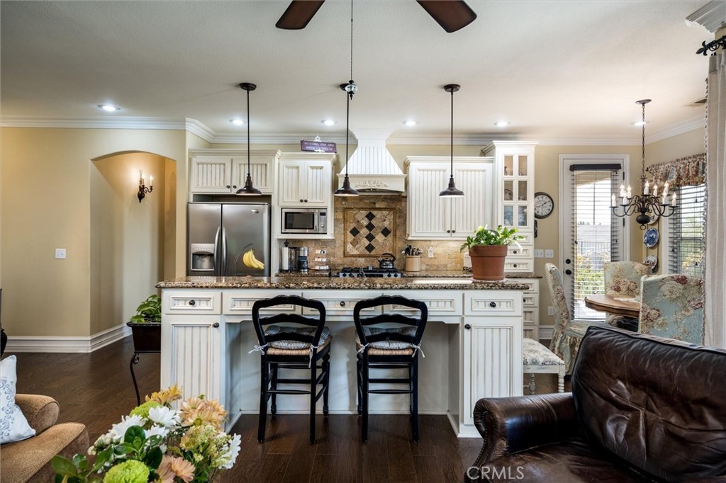14787 Wood Road Riverside, CA 92508 - Photo 41 of 64 a kitchen with stainless steel appliances granite countertop a refrigerator a sink dishwasher a stove and a dining table with wooden floor