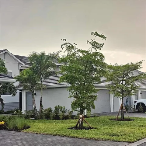 a front view of a house with a yard and palm trees