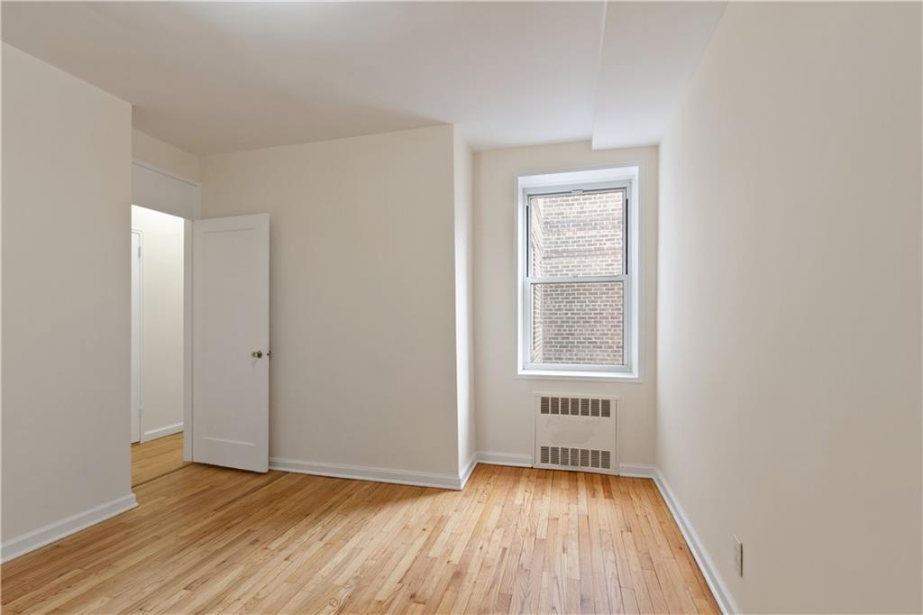 6801 Shore Road, Unit 5U Brooklyn, NY 11220 - Photo 18 of 21 a view of an empty room with wooden floor and a window
