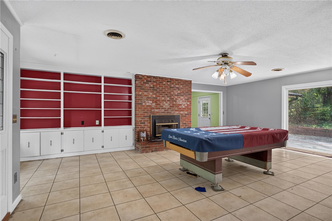 123 Robin Road Westminster, SC 29693 - Photo 11 of 50 A spacious recreation room features a brick fireplace and built-in shelving, providing a cozy entertainment area.