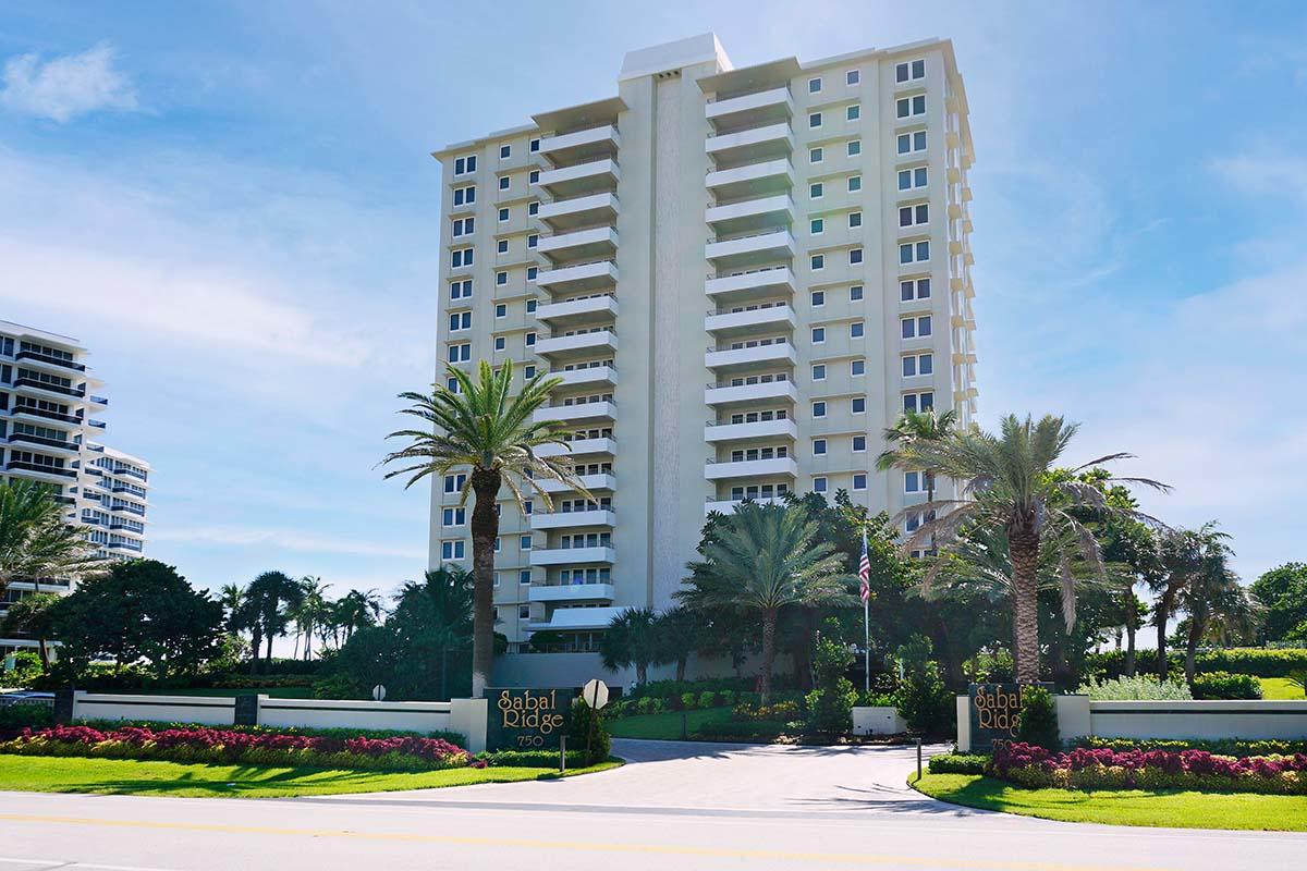 a front view of a residential apartment building with a yard and palm trees
