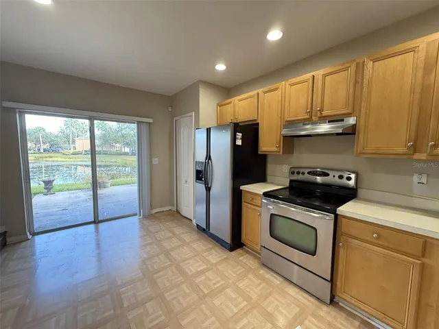 a kitchen with stainless steel appliances granite countertop a stove a refrigerator a sink and a cabinets with wooden floor