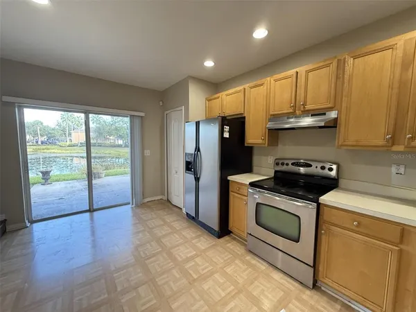 a kitchen with stainless steel appliances granite countertop a stove a refrigerator a sink and a cabinets with wooden floor