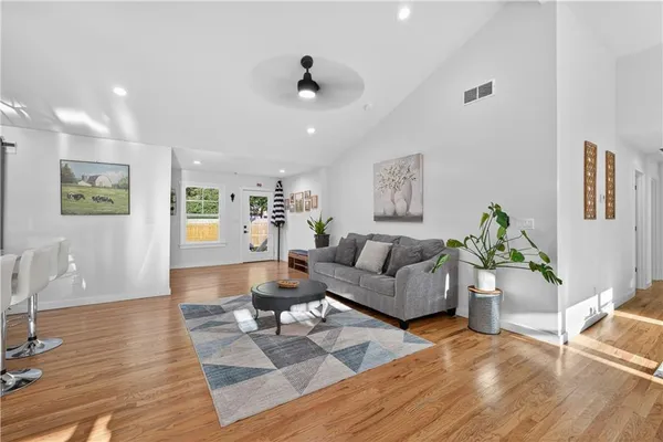 a kitchen with stainless steel appliances kitchen island granite countertop a refrigerator a stove and white cabinets with wooden floor