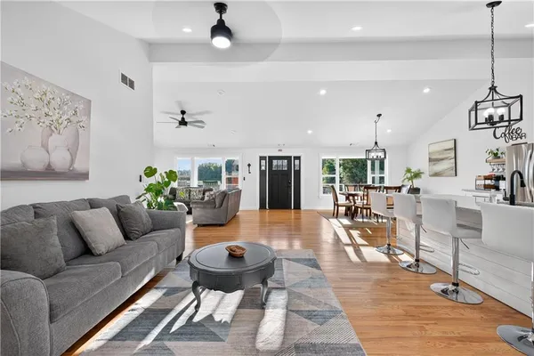 a kitchen with stainless steel appliances granite countertop a refrigerator a stove and a dining table with wooden floor