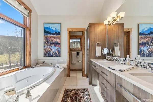 a spacious bathroom with a granite countertop tub double vanity sink and a large mirror