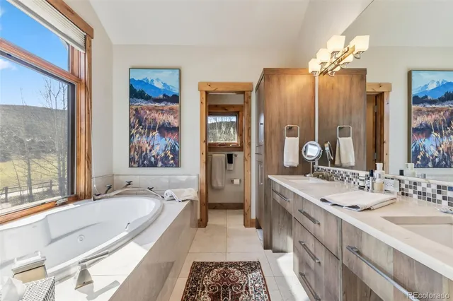 a spacious bathroom with a granite countertop tub double vanity sink and a large mirror