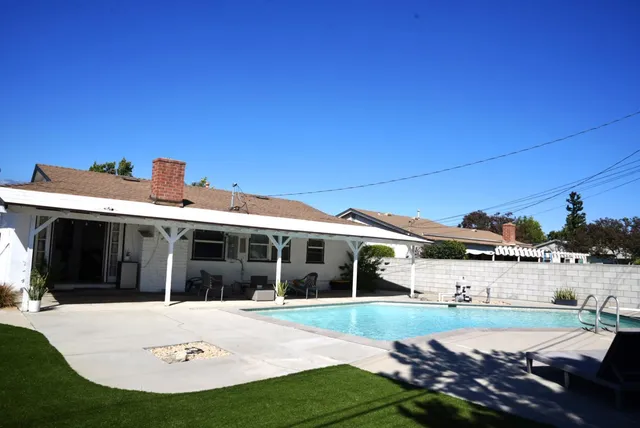 a view of a white house with a big yard and potted plants