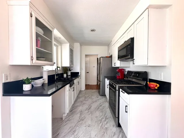 a kitchen with granite countertop a sink a stove top oven a counter space and cabinets
