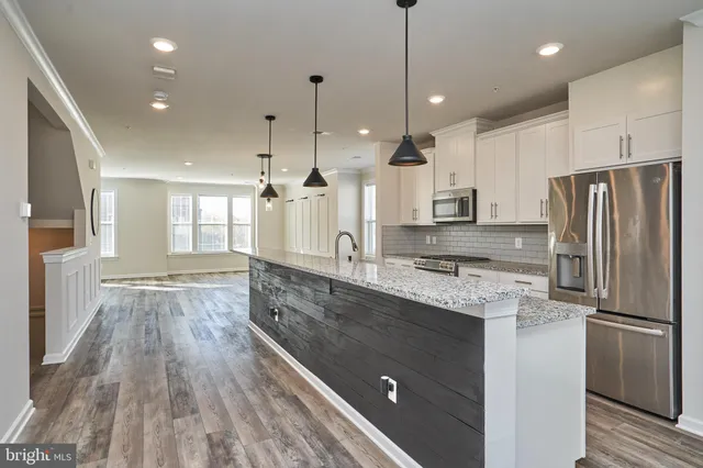 a large kitchen with kitchen island a stove a sink a center island and wooden floor