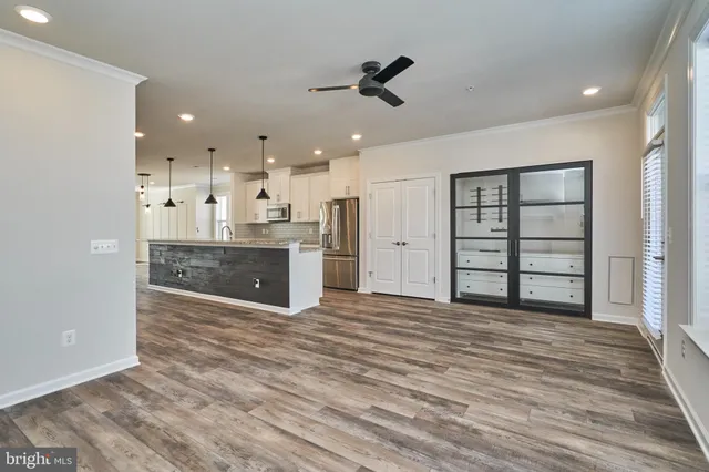 a large kitchen with stainless steel appliances kitchen island granite countertop a refrigerator a oven and a wooden floors
