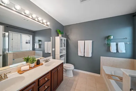 a spacious bathroom with a double vanity sink toilet and a mirror