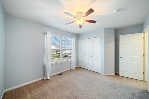 an empty room with windows and ceiling fan