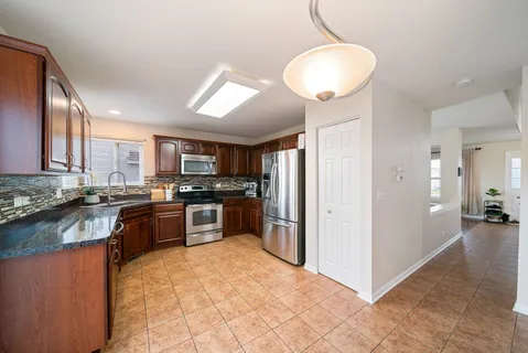 a kitchen with stainless steel appliances granite countertop a refrigerator a stove a sink and a microwave