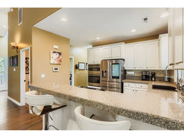 a kitchen with stainless steel appliances granite countertop a sink refrigerator and cabinets