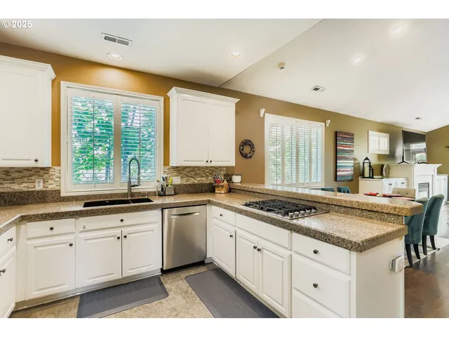 a kitchen with a stove a sink a refrigerator and white cabinets with wooden floor