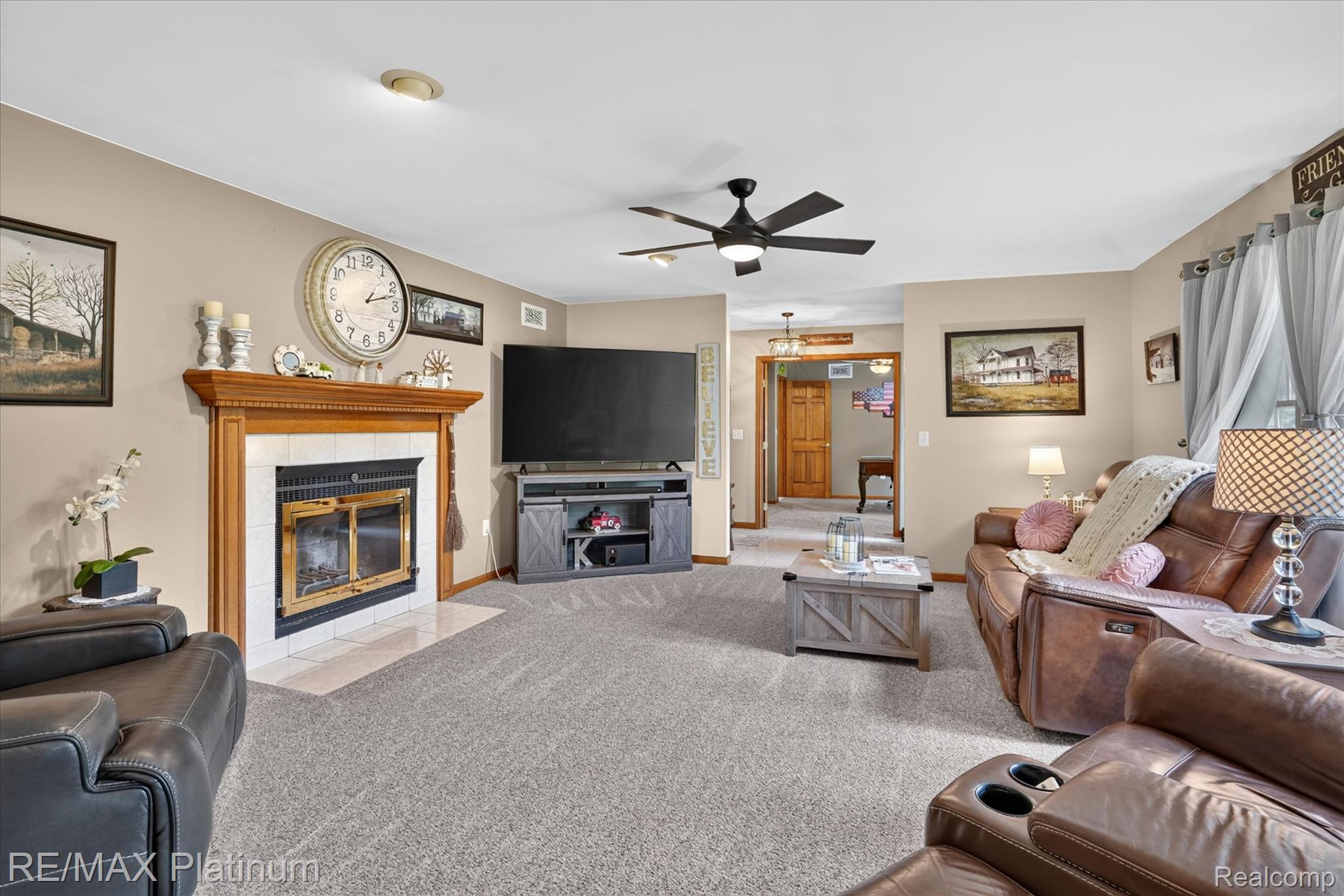 4457 Bradley Road Gregory, MI 48137 - Photo 5 of 79 Living area featuring a fireplace with a wood mantel and white tiled surround, soft gray carpeting, a ceiling fan with integrated lighting, and neutral wall tones