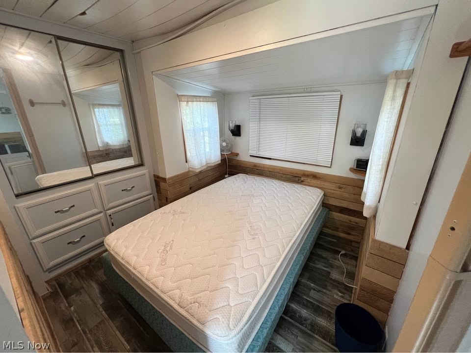 6684 Leon Road, Unit 336 Andover, OH 44003 - Photo 4 of 10 Bedroom with dark wood finished floors, a closet, a wainscoted wall, and wood walls