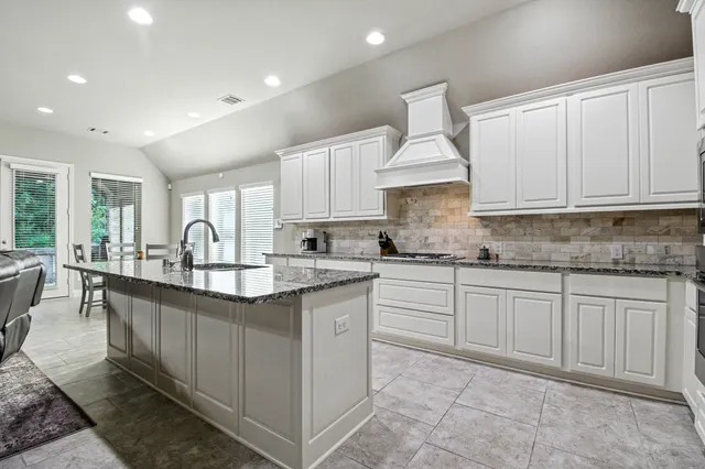 a kitchen with granite countertop a sink white cabinets and chairs