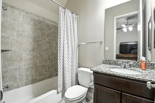 a bathroom with a granite countertop sink toilet and shower