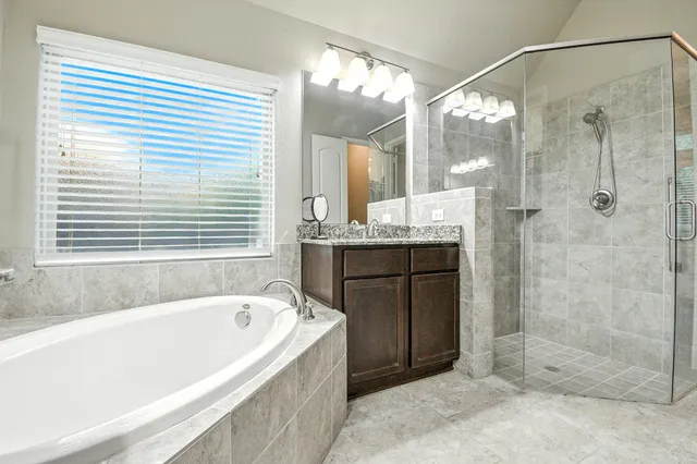 a bathroom with a granite countertop tub shower and sink