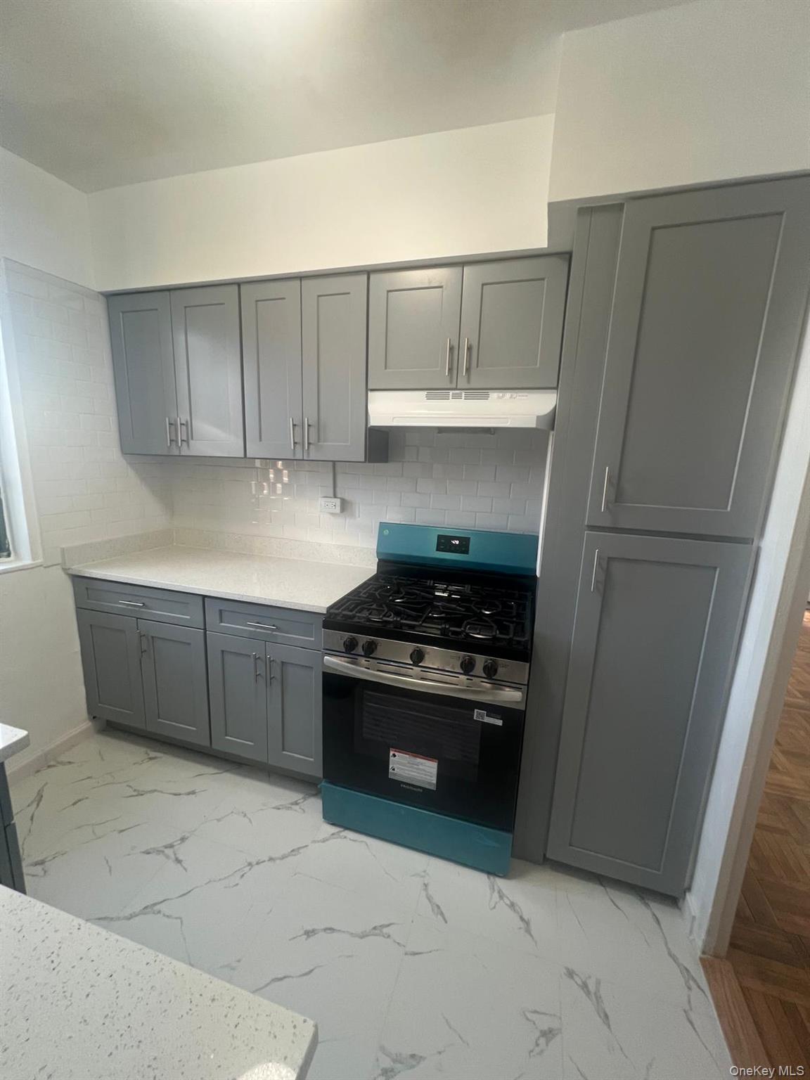1314 Virginia Avenue, Unit 4F Bronx, NY 10462 - Photo 8 of 17 Kitchen with gray cabinets, stainless steel gas range oven, light marble finish flooring, and decorative backsplash