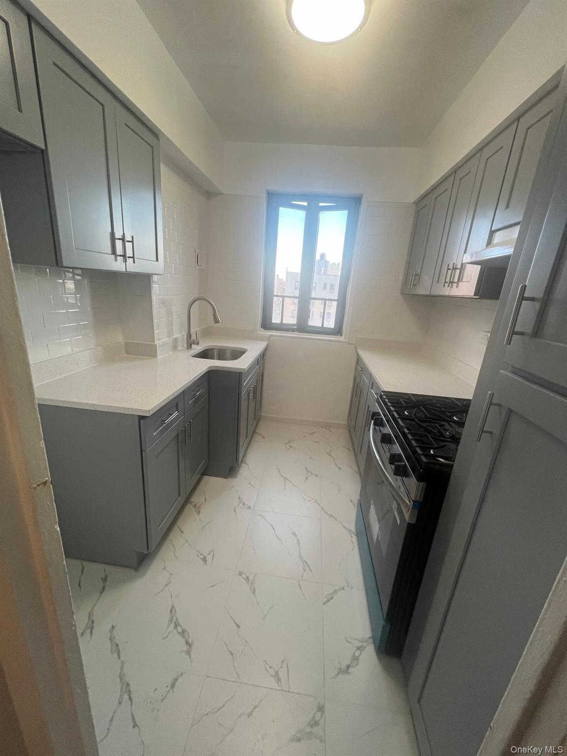 1314 Virginia Avenue, Unit 4F Bronx, NY 10462 - Photo 10 of 17 Kitchen featuring gray cabinets, light marble finish floors, black range with gas stovetop, and light stone countertops